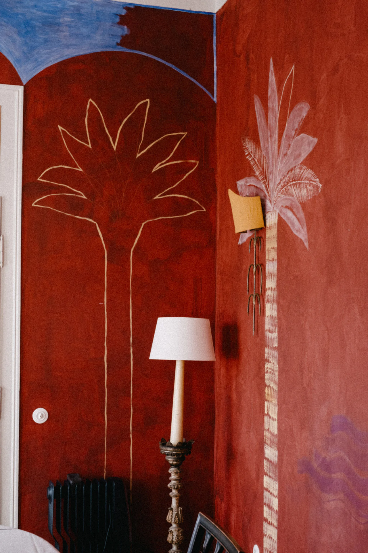 A red wall with palm trees painted on it.