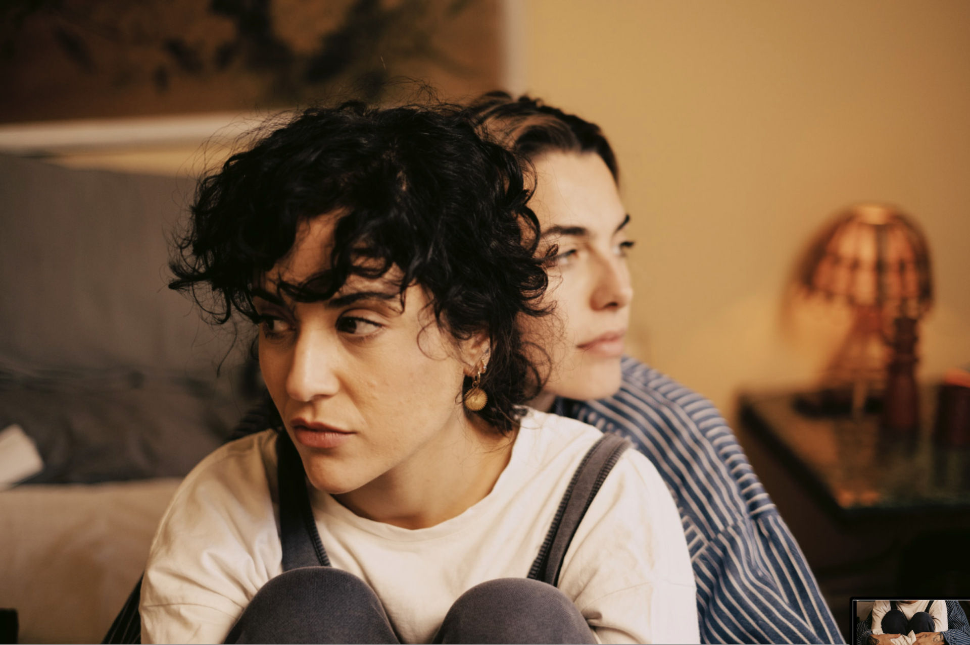 Two women sitting on a couch looking at each other.