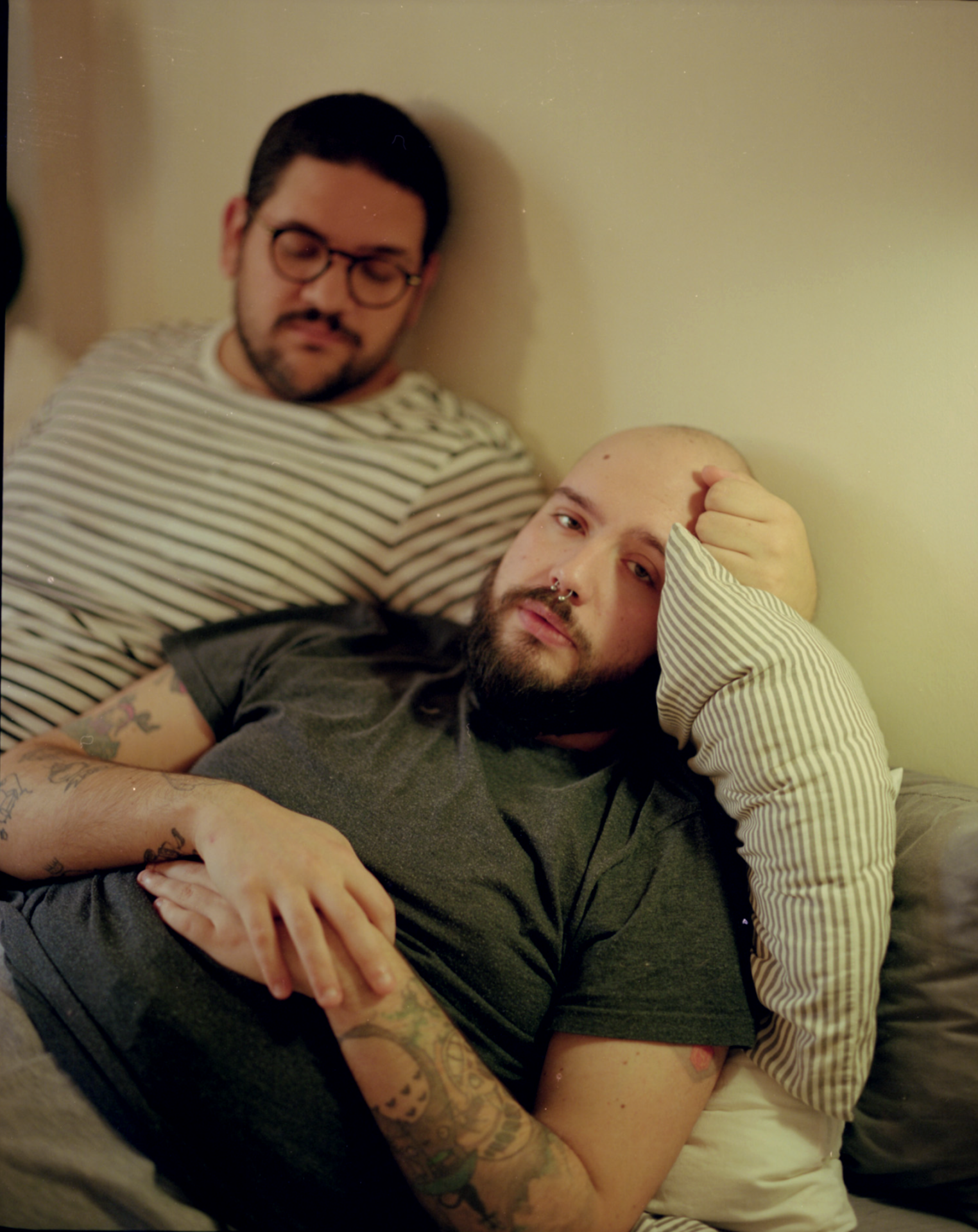 Two men laying on a bed.