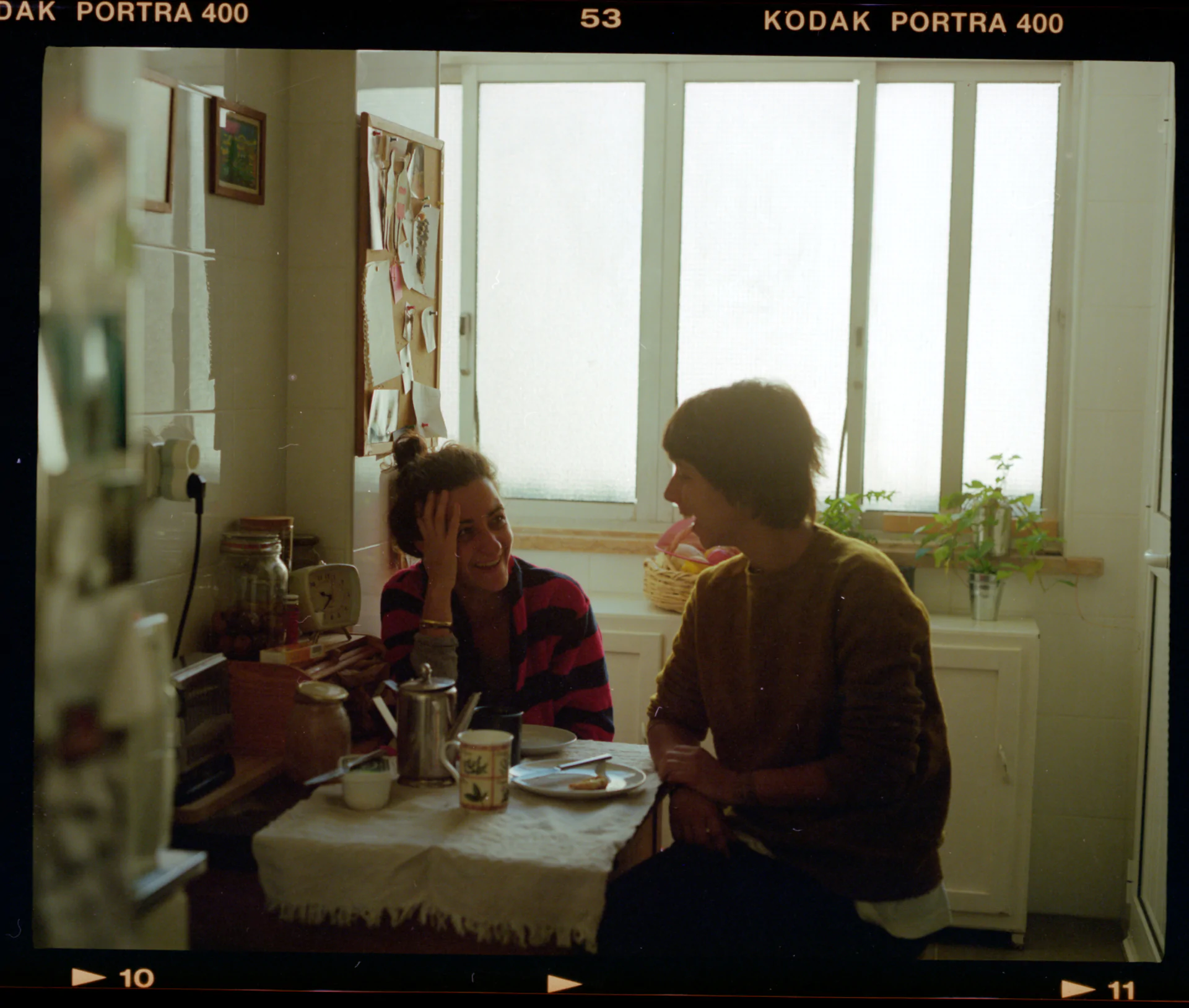 Two women sitting at a table in a kitchen.