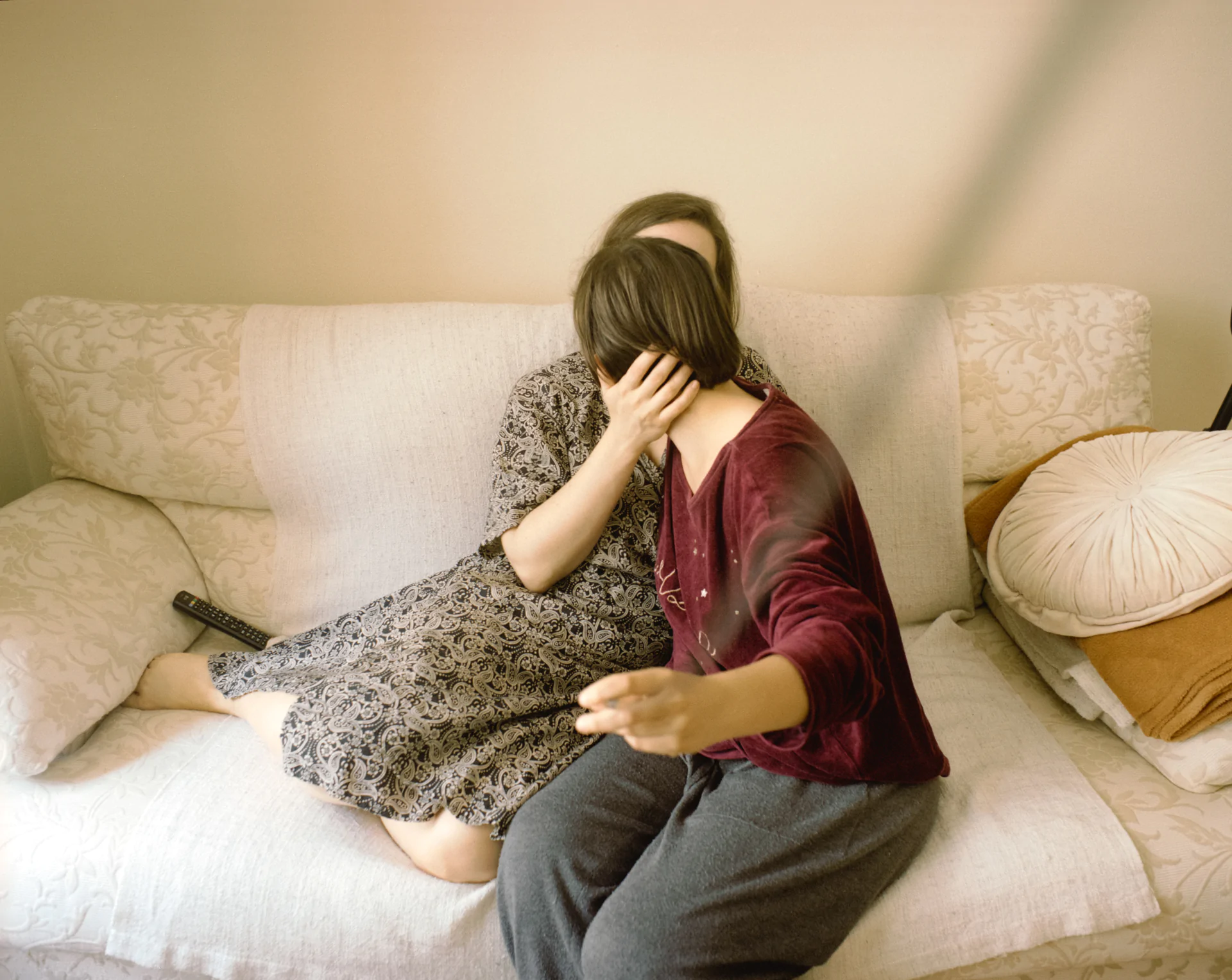Two women sitting on a couch with a knife in their hands.