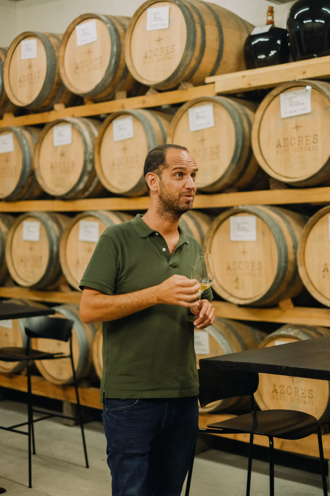 A man standing in front of wine barrels.