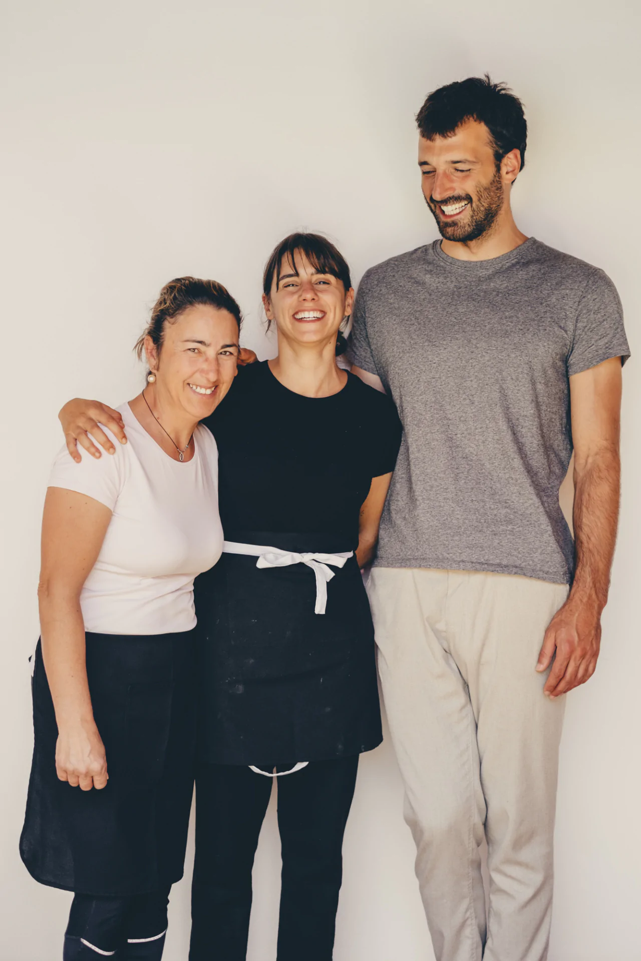 Three people standing in front of a white wall.