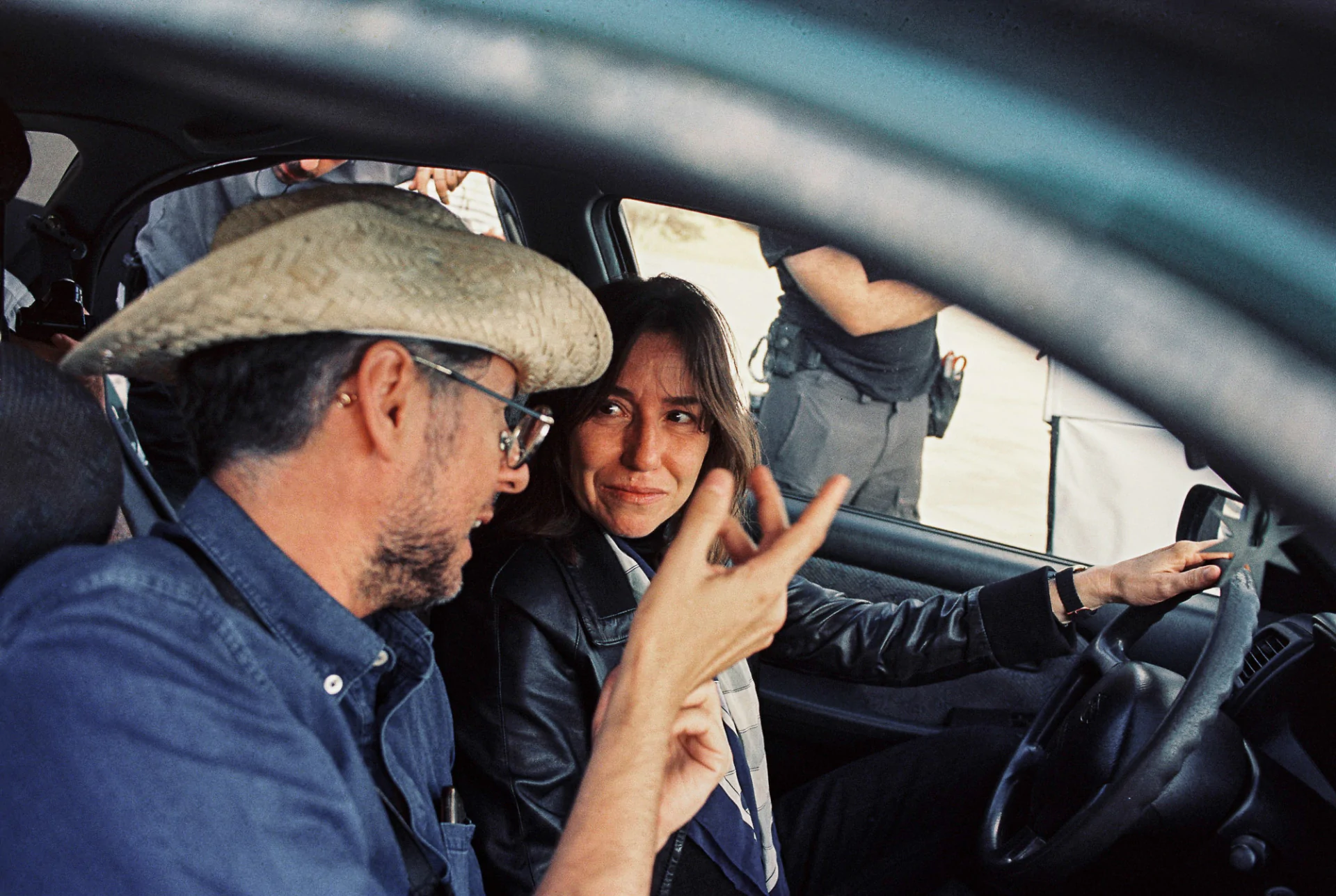 A man and woman in a car talking to each other.