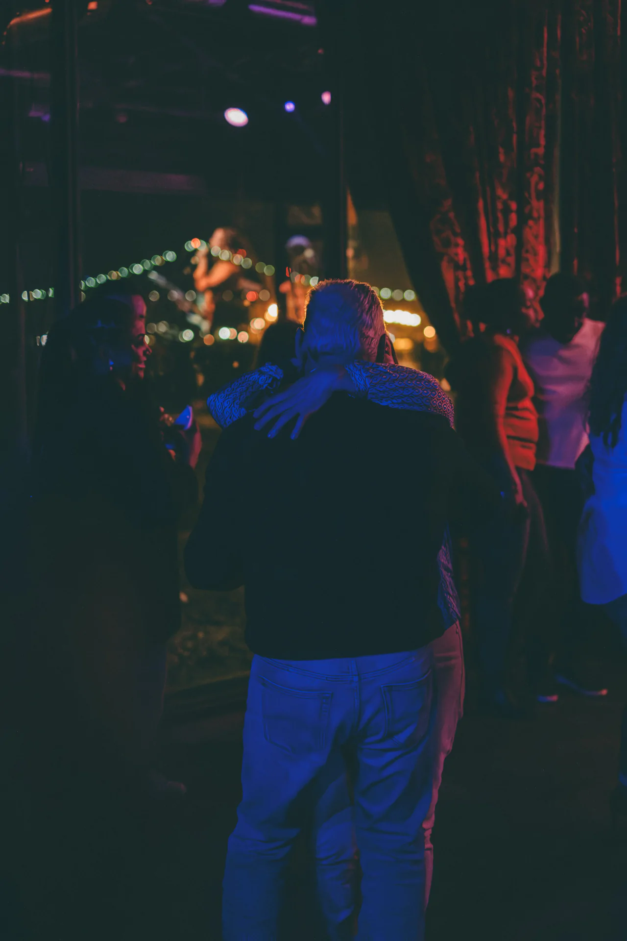 A group of people hugging at a nightclub.
