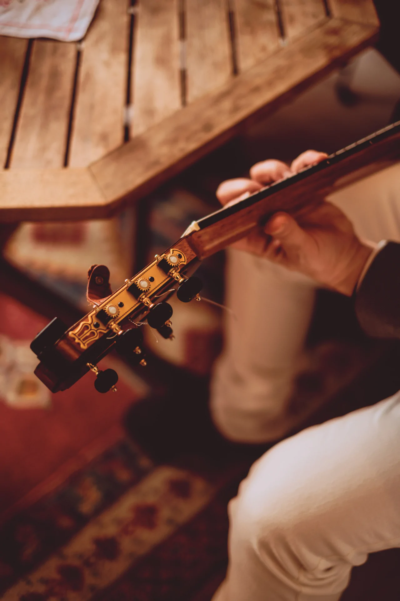 A person playing a guitar on a wooden table.