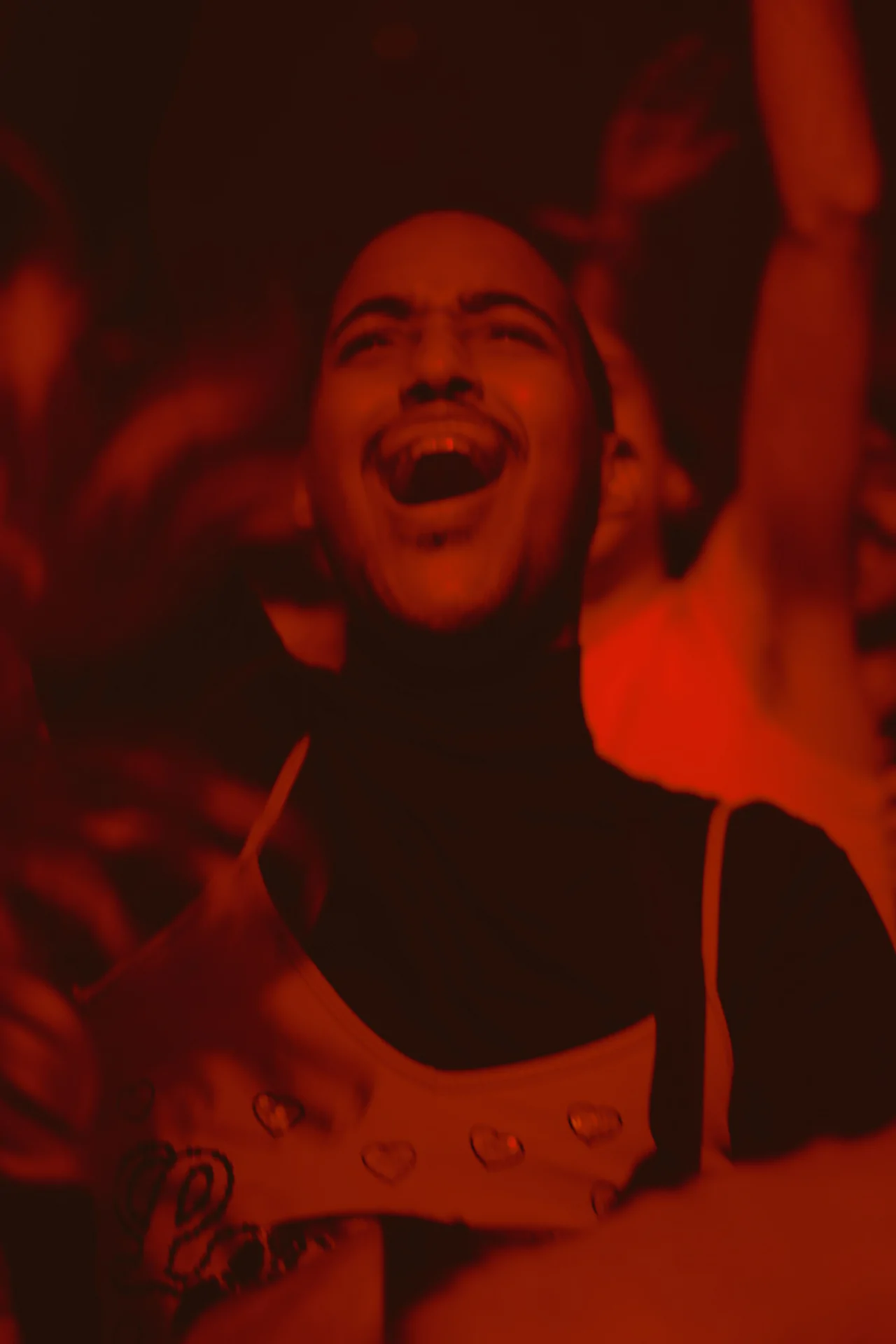 A man in a red shirt is laughing in a crowd.