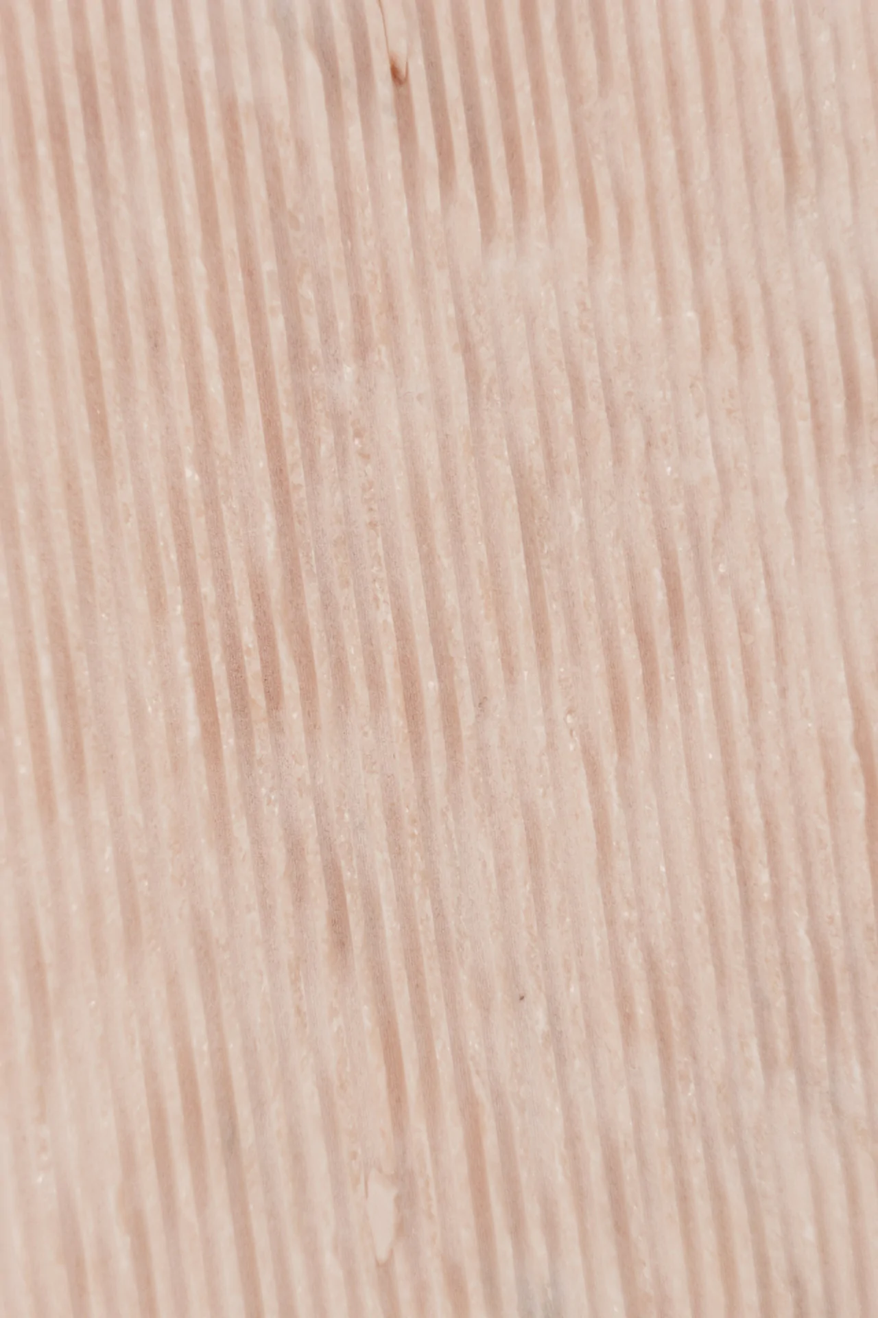 Close-up of a textured surface with parallel, wavy lines. The color is a light beige, resembling ripples in sand or a fabric pattern.