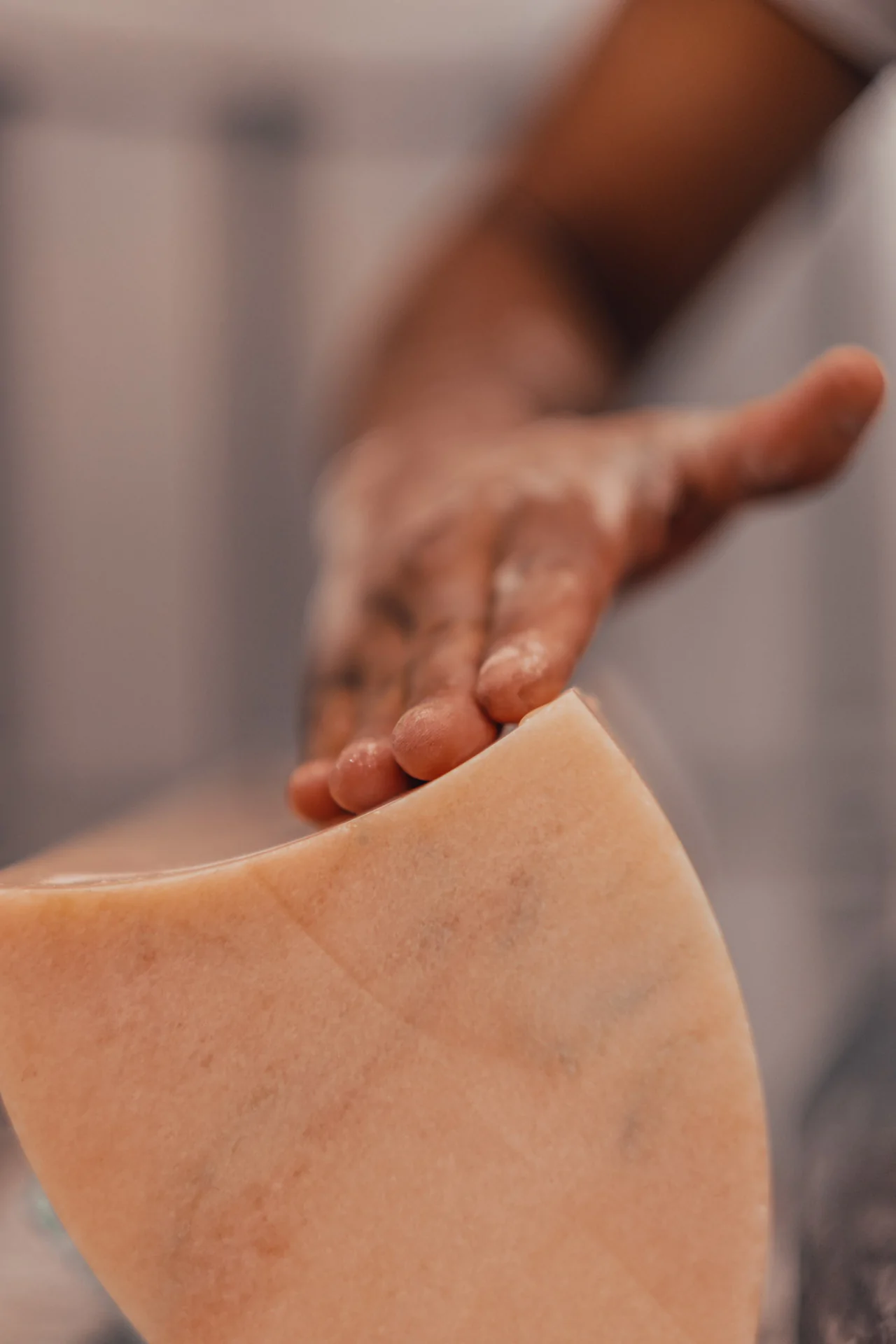 Craftsman's hands delicately touching marble surface during creation of Cartier Trinity Ring anniversary table