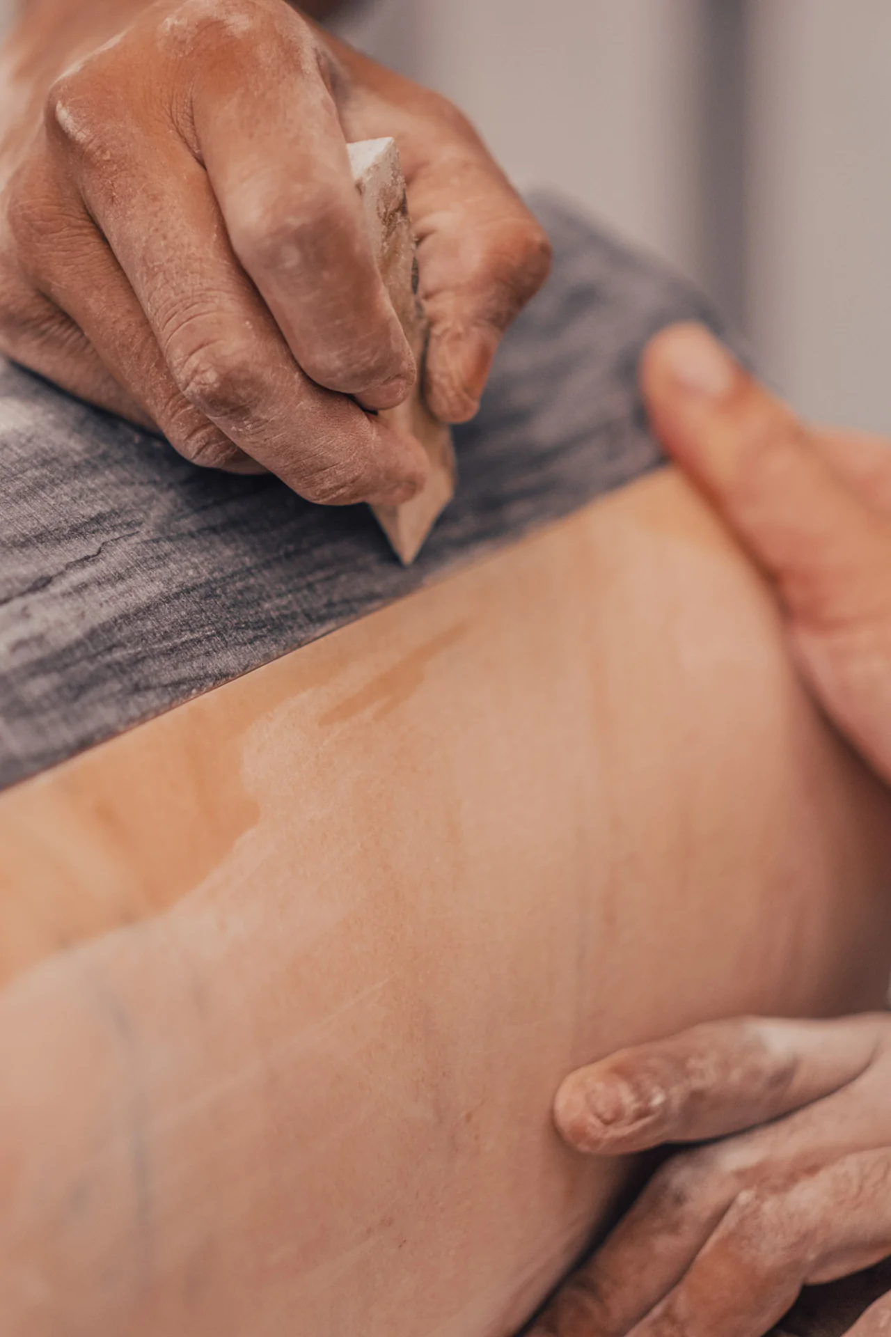 Craftsman's hands delicately touching marble surface during creation of Cartier Trinity Ring anniversary table