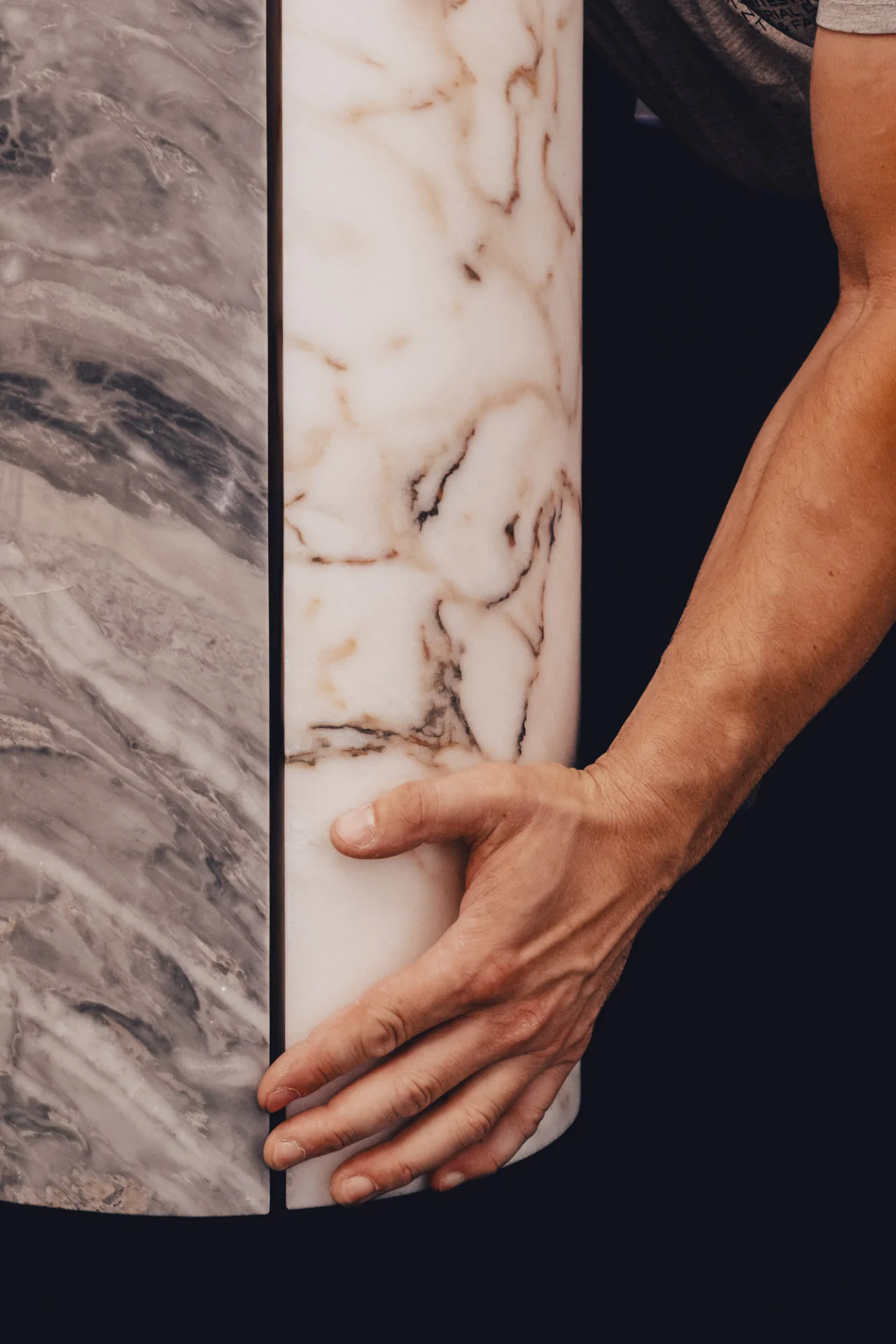 Craftsman's hands delicately touching marble surface during creation of Cartier Trinity Ring anniversary table