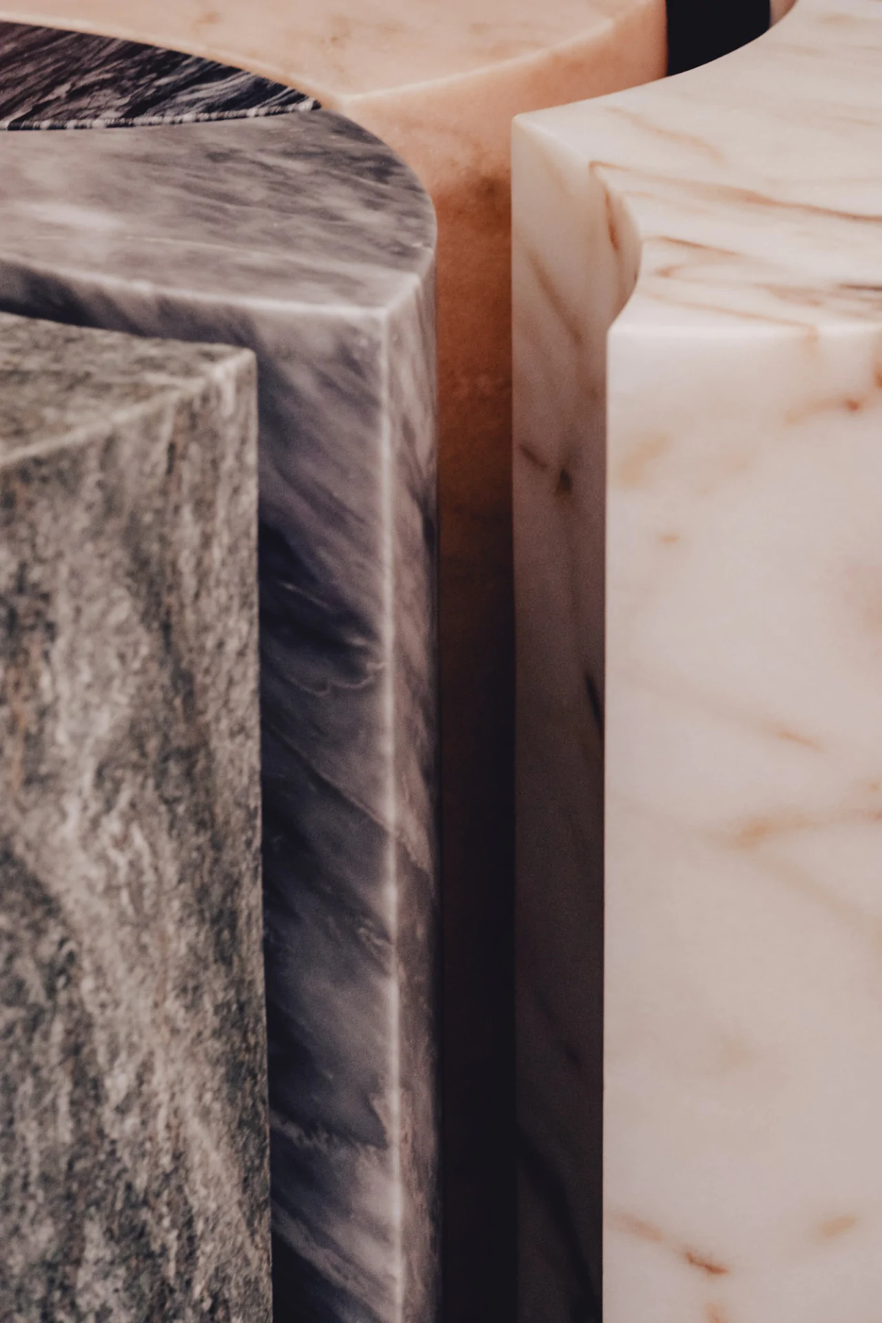 Close-up of three marble pillars in gray, pink, and white, showcasing their textures and natural patterns.