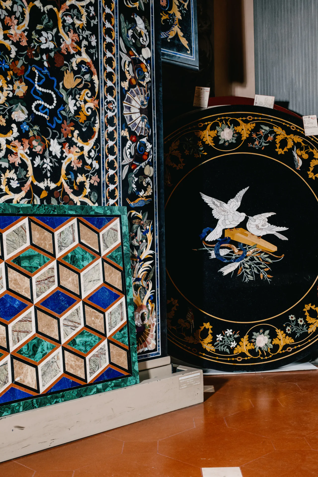 A variety of intricate mosaic designs displayed vertically against a wall, featuring geometric patterns and floral motifs.