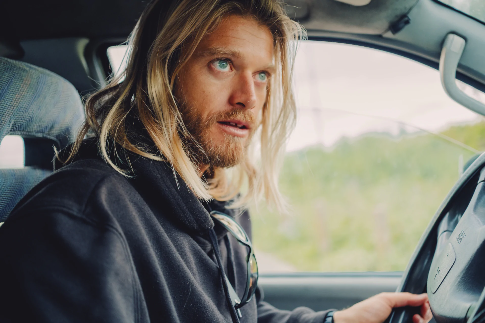 Surf instructor in car looking through window Portuguese coast road trip