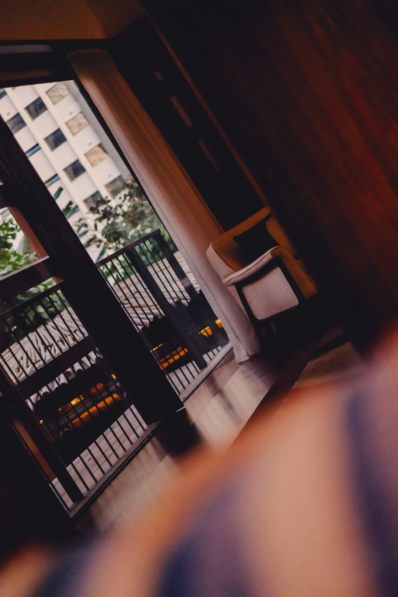 A modern room with a balcony view of an apartment building, featuring a large window, curtain, armchair, and railing outside—perfect for luxury hotel photography São Paulo or Rosewood São Paulo photography enthusiasts.