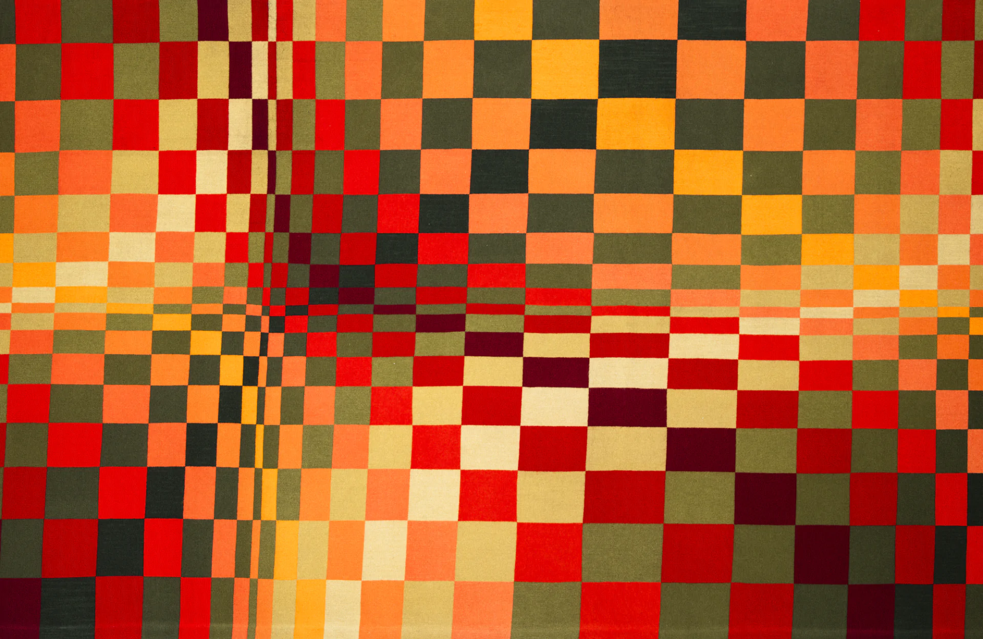 Colorful grid of red, orange, yellow, and green squares arranged in a checkered pattern, forming an abstract, geometric design.